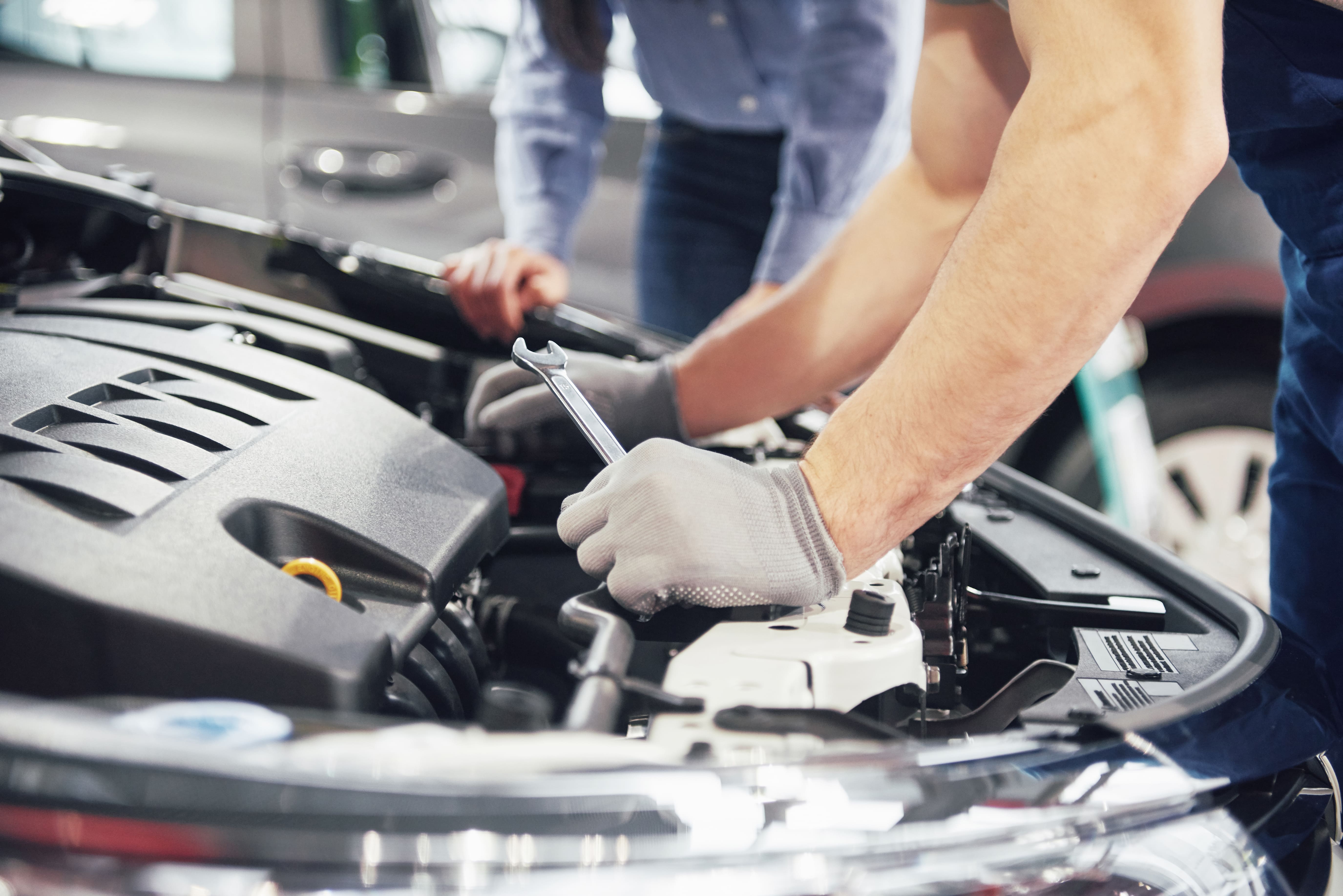 man-mechanic-woman-customer-look-car-hood-discuss-repairs